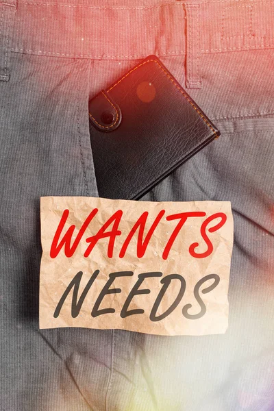 Word writing text Wants Needs. Business concept for to have something necessary or desire for the individual to live Small little wallet inside man trousers front pocket near notation paper. — Stock Photo, Image