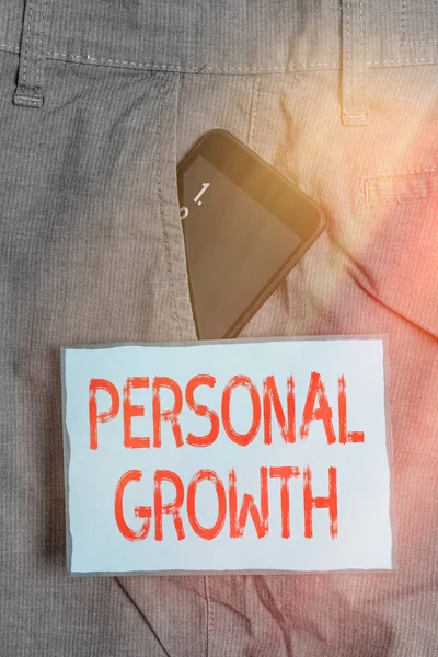 Handwriting text writing Personal Growth. Concept meaning a longterm process which shows the development of a Smartphone device inside formal work trousers front pocket near note paper.