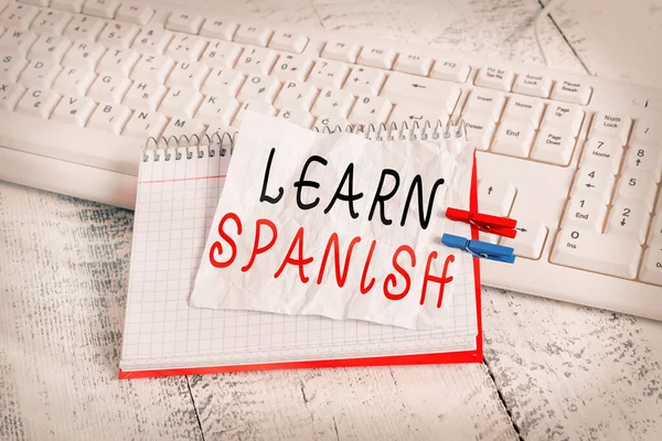El yazısı metni İspanyolca öğren. İspanya 'nın ulusal dilini konuşmayı ve yazmayı öğretmeyi amaçlayan kavram. Kağıt hatırlatma, mandal iğneli beyaz klavye hafif ahşap.. — Stok fotoğraf