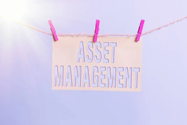 Word writing text Asset Management. Business concept for precise handling of resources for future economic benefits Clothesline clothespin rectangle shaped paper reminder white wood desk.