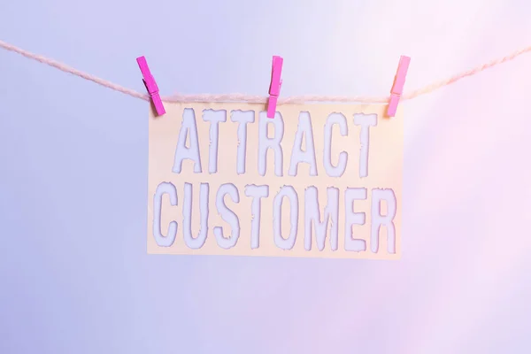 Word writing text Attract Customer. Business concept for enthusiasm and appeal in marketing draw attention to buyer Clothesline clothespin rectangle shaped paper reminder white wood desk.