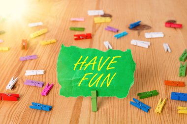 Kelime yazma metni. İyi eğlenceler. Kendine eğlence ve eğlence sağlayan bir iş konsepti. Renkli çamaşır iğnesi kağıtları boş ahşap zemin ofisini hatırlatıyor..