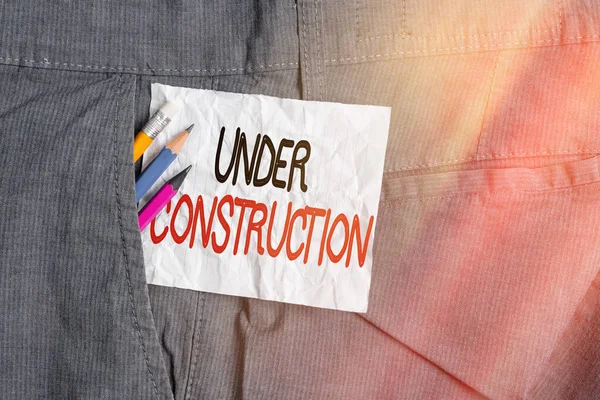 Text sign showing Under Construction. Conceptual photo building that is unfinished but actively being worked on Writing equipment and white note paper inside pocket of man work trousers. — Stock Photo, Image