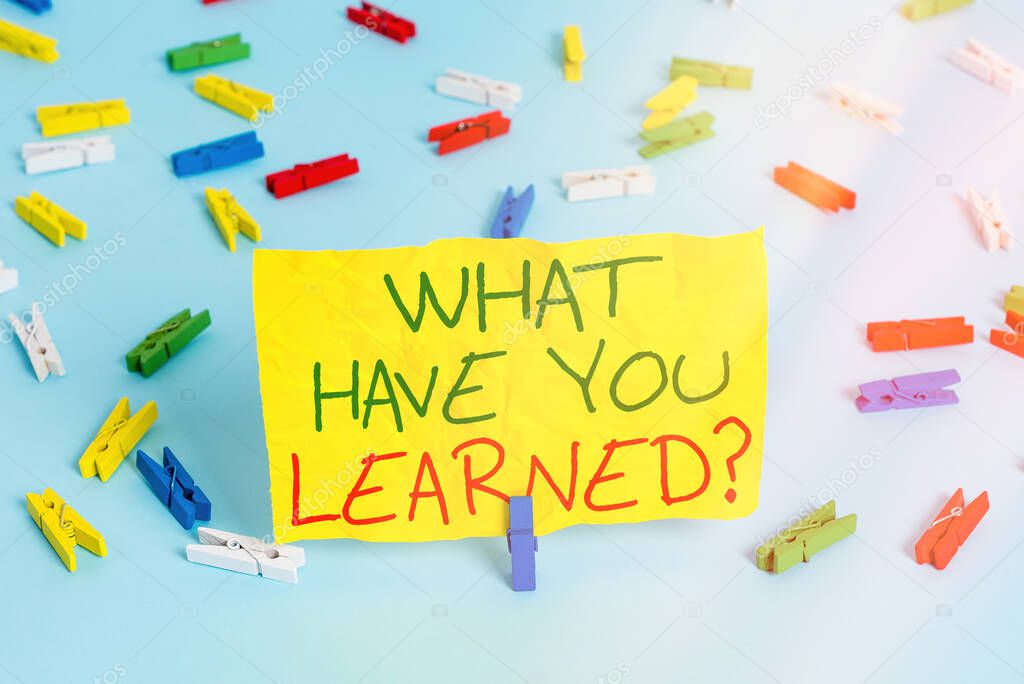 Handwriting text writing What Have You Learned Question. Concept meaning to know the things acquire or absorb Colored clothespin papers empty reminder blue floor background office pin.