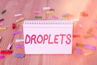 Damlacıklar 'ın el yazısı. Belirli ıslak yerlerde çok küçük bir sıvı damlası bulunabilir. Renkli çamaşır iğnesi kağıtları boş ahşap zemin ofisini hatırlatır..