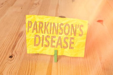 Parkinson hastalığını gösteren kavramsal el yazısı. İş fotoğrafı metni kronik ilerici nörolojik hastalık sonraki hayatın ahşap zemin zemin arka plan yeşil çamaşır mandalı oyuk ofisi.