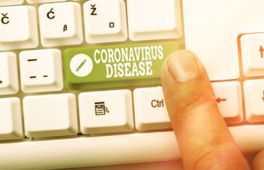 Coronavirus Hastalığı el yazısı. Yeni bir virüs olan SARSCoV2 beyaz pc klavyesinin beyaz tuş alanının üzerinde boş not kağıdı bulunan hastalık olarak tanımlanan kavram.