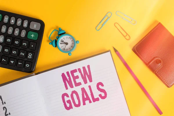 Handwriting text New Goals. Concept meaning a list of clearlydefined plans that an individual should attain Open notebook wallet calculator clips pencil alarm clock color background.