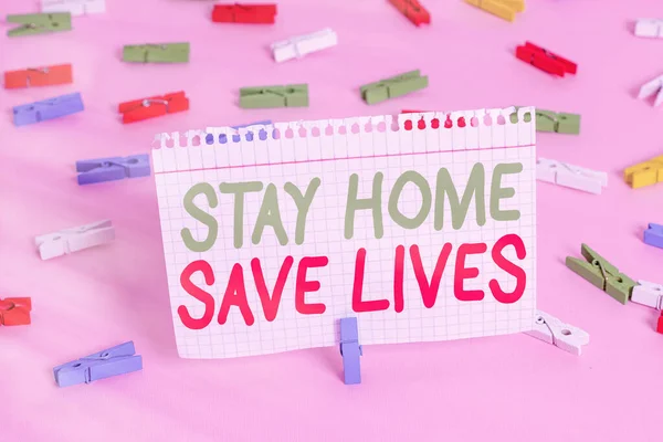 Χειρόγραφο κείμενο Μείνε σπίτι σώσε ζωές. Έννοια που σημαίνει μείωση του αριθμού των ασθενών που έχουν μολυνθεί με το να μην αφήνει το σπίτι Χρωματιστά χαρτιά clothespin κενό υπενθύμιση ροζ πάτωμα φόντο καρφίτσα γραφείου. — Φωτογραφία Αρχείου