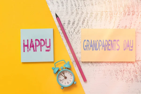 Tulisan tangan menulis Happy Grandparents Day. Konsep yang berarti Orang Tua atau perayaan warga senior Notepads Penanda kertas berwarna lembar alarm jam latar belakang kayu. — Stok Foto