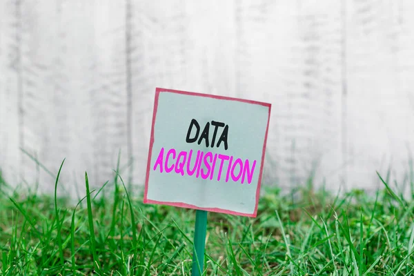 Word writing text Data Acquisition. Business concept for way to obtain statistics that can be maneuvered digitally Plain empty paper attached to a stick and placed in the green grassy land.