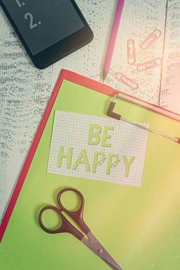 Mutlu Ol tabelası. Belirli bir şey veya olay üzerine zevk ve memnuniyeti gösteren kavramsal fotoğraf. Pano kağıdı, kalem akıllı telefon makası. Tahta arka plan kırpıntıları..