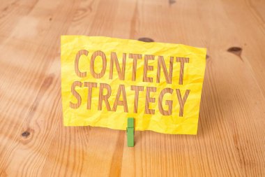 İçerik Stratejisini gösteren kavramsal el yazısı. İş fotoğrafı önemli pazarlama yaklaşımı alıcı çekmek için dağıtıldı ahşap zemin zemin arkaplan yeşil çamaşır tokası oluk ofis.