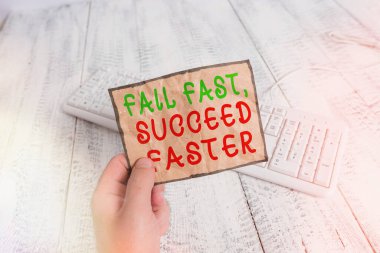 Conceptual hand writing showing Fail Fast, Succeed Faster. Business photo text failed attempt increases an eventual success Man holding colorful reminder square shaped paper wood floor. clipart