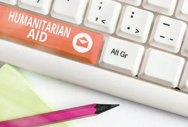 "Conceptual hand writing showing Humanitarian Aid". Photo d'affaires montrant l'assistance immédiate fournie après une catastrophe naturelle et d'origine humaine Clavier pc blanc avec papier note au-dessus de la copie à clé blanche — Photo