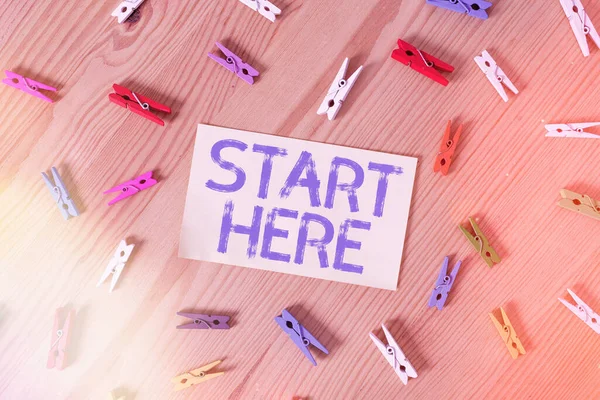 Handschrifttekst Begin hier. Concept betekent een handeling van het wijzen van een locatie of een deel van waar te beginnen Gekleurde wasknijpers lege herinnering houten vloer achtergrond kantoor. — Stockfoto