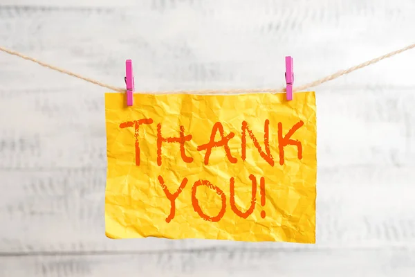 Word writing text Thank You. Business concept for polite expression to acknowledge a gift, service or compliment Clothesline clothespin rectangle shaped paper reminder white wood desk. Stock Image