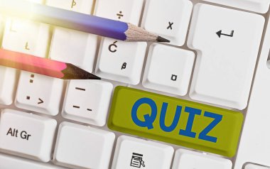 Quiz 'i gösteren kavramsal el yazısı. Oyuncuların sorulara doğru cevap vermeye çalıştıkları beyaz pc klavye üzerinde beyaz tuş kopyalama alanının üzerinde boş not kağıdı ile oyunun iş metni biçimi.