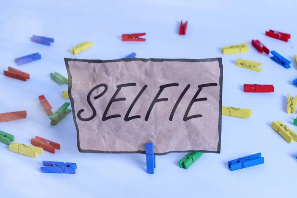 Word writing text Selfie. Business concept for taken by oneself using a digital camera for posting on social network Colored clothespin papers empty reminder white floor background office.