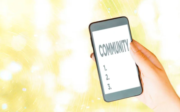 Handwriting text writing Community. Concept meaning group of showing living in one place having a characteristic in common Modern gadgets with white display screen under colorful bokeh background.