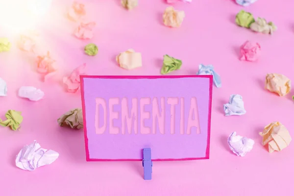 Writing note showing Dementia. Business photo showcasing the general word for diseases and disorders with a loss in memory Colored crumpled papers empty reminder pink floor background clothespin. — Stock Photo, Image