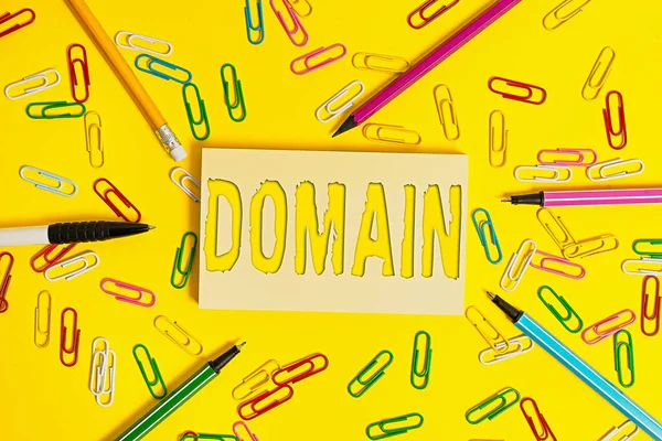 Conceptual hand writing showing Domain. Business photo showcasing identification string that defines a realm of administrative autonomy Flat lay above empty paper with pencils and paper clips. — Stock Photo, Image