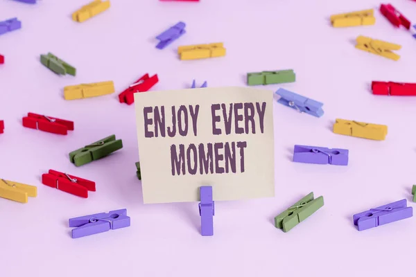 Word writing text Enjoy Every Moment. Business concept for stay positive thinking for an individualal development Colored clothespin papers empty reminder white floor background office. — Stock Photo, Image