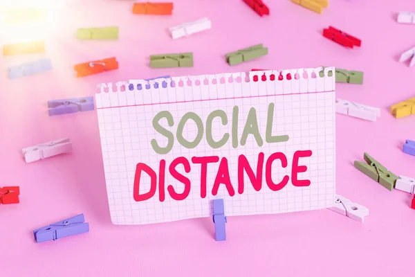 Handwriting text Social Distance. Concept meaning maintaining a high interval physical distance for public health safety Colored clothespin papers empty reminder pink floor background office pin.