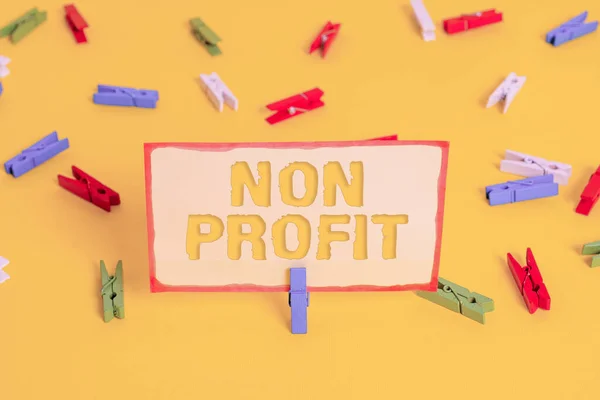 Begrebsmæssig håndskrift viser Non Profit. Business foto tekst en aktivitet, der ikke gør eller udføres primært for en fortjeneste Farvede clothespin papirer tomme påmindelse gul gulv kontor. - Stock-foto