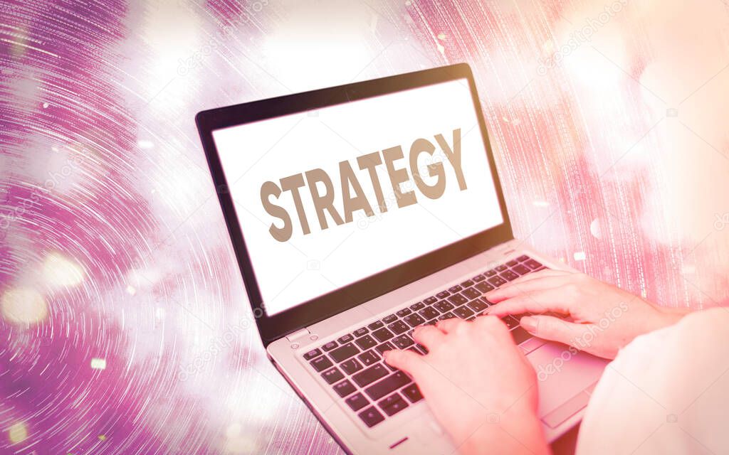 Handwriting text writing Strategy. Concept meaning action plan or strategy designed to achieve an overall goal Modern gadgets with white display screen under colorful bokeh background.