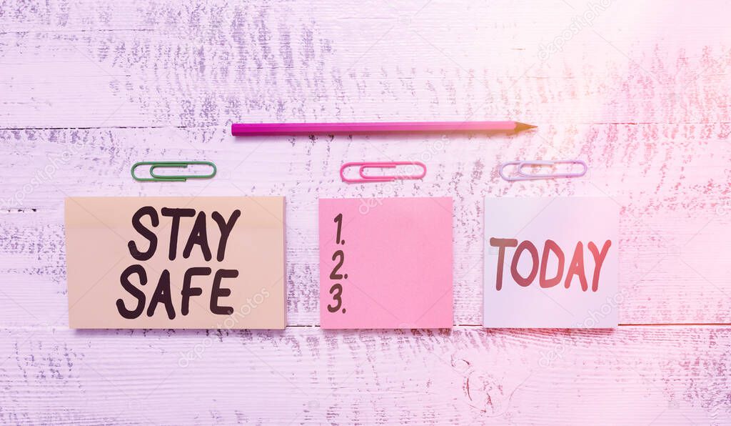 Text sign showing Stay Safe. Conceptual photo secure from threat of danger, harm or place to keep articles Multicolor blank notepads clips marker pencil wooden vintage background.