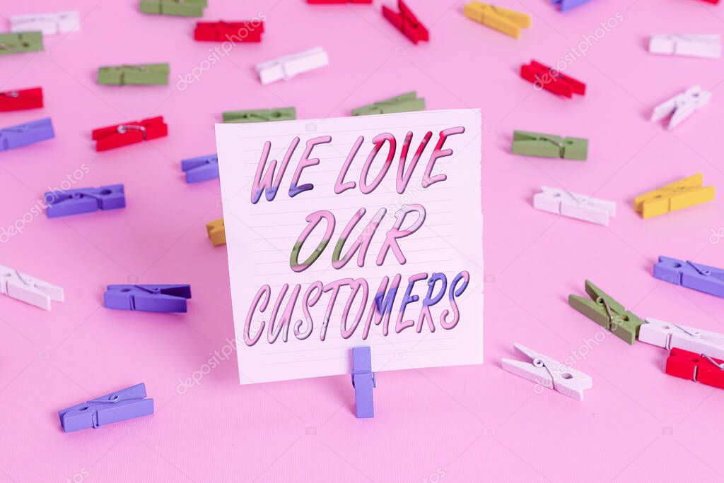 Word writing text We Love Our Customers. Business concept for clients care and attention Good customer services Colored clothespin papers empty reminder pink floor background office pin.