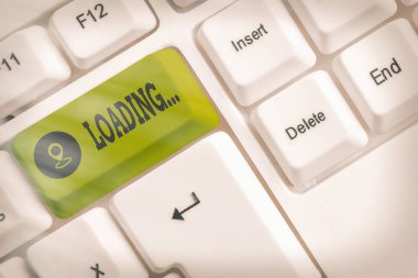 Yüklemeyi gösteren not... Beyaz pc klavyesini beyaz tuş alanının üzerinde boş not kağıdıyla dengelemek için ekstra bir miktar uygulayan iş fotoğrafı gösterimi.