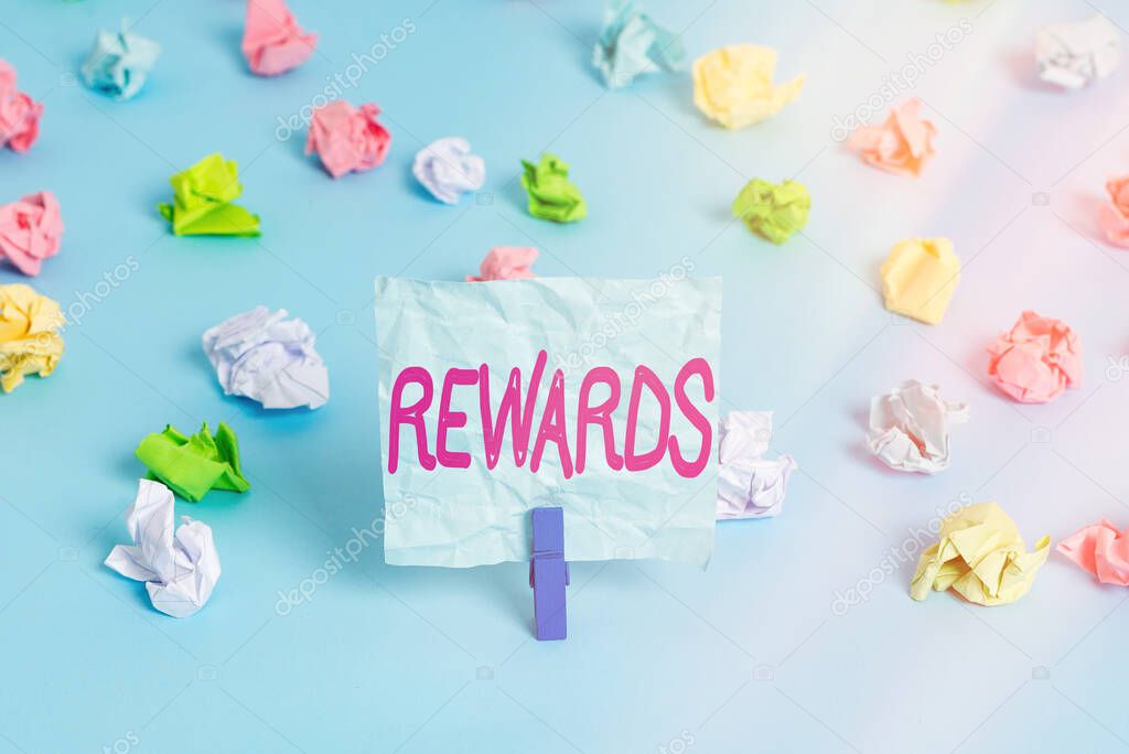 Handwriting text Rewards. Concept meaning certain number or percentage you earn for every dollar you charge Colored crumpled papers empty reminder blue floor background clothespin.