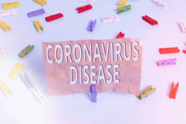 Coronavirüs Hastalığı belirtileri. Yeni bir virüs olan SARSCoV2 'nin yol açtığı hastalık olarak tanımlanan kavramsal fotoğraf renkli çamaşır iğnesi kağıtları boş mavi zemin ofis pimi.