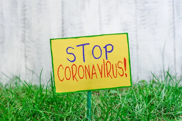 Skriva text och stoppa Coronavirus. Begreppet betyder medvetandegörande av sjukdomar kamp för att minska COVID19 fall Plain tomt papper fäst vid en pinne och placeras i den gröna gräsbevuxen mark. — Stockfoto