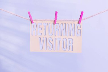 Kelime yazma metni Ziyaretçi Dönüşü. Daha önce kimin ziyaret ettiği ve sitenize geri döndüğü ile ilgili iş konsepti Çamaşır ipi çamaşır mandalı şekilli kağıt hatırlatıcı beyaz ahşap masa.