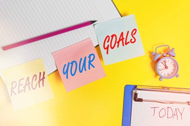 Handwriting text writing Reach Your Goals. Concept meaning Business and success, Focus with determination to build your future Flat lay above table with blank papers with copy space for text messages. clipart