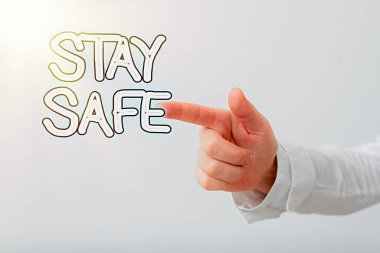 Stay Safe 'i gösteren bir not yazıyorum. İş fotoğrafı gösterimi tehlike, zarar ya da malzeme saklama tehdidinden korunuyor. Model, seyrüsefer ilerlemesini sembolize eden bir el ile gösteriliyor..