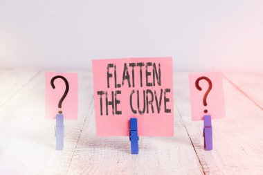 Eğri Düz 'ü gösteren metin işareti. Kavramsal fotoğraf, ahşap masaya yerleştirilmiş ataçlarla karalanmış ve ufalanan çarşaf ile bulaşıcı hastalığın hızını yavaşlatmaya yönelik bir farkındalık yaratıyor..