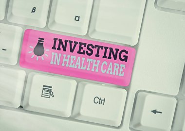 Sağlık hizmetlerine yatırım yapıldığını gösteren kavramsal el yazısı. İş fotoğrafı metni, beyaz tuş kopyalama alanının üzerinde boş not kağıdı bulunan sağlık hizmetleri veya iyileştirme üzerine para koydu.