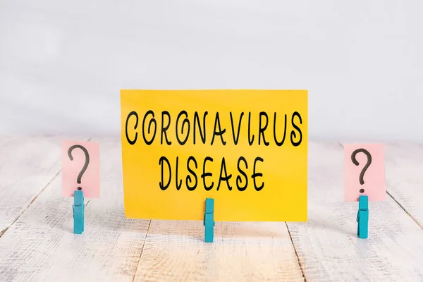 Konceptuell handstil som visar Coronavirus sjukdom. Företagsfoto text definieras som sjukdom som orsakas av ett nytt virus SARSCoV2 Smulande blad med gem placeras på träbordet. — Stockfoto