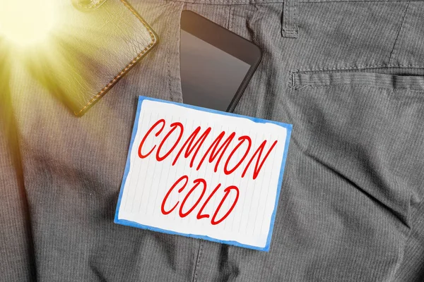 Text sign showing Common Cold. Conceptual photo viral infection in upper respiratory tract primarily affecting nose Smartphone device inside trousers front pocket with wallet and note paper.