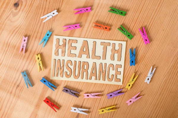 健康保険を示すテキスト記号。被保険者の医療費を融資するための概念的な写真システム色の布の紙空のリマインダ木製の床の背景オフィス. — ストック写真