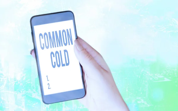 Conceptual hand writing showing Common Cold. Business photo text viral infection in upper respiratory tract primarily affecting nose Modern gadgets white screen under colorful bokeh background.