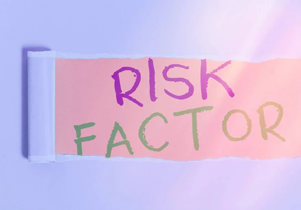 Handwriting text writing Risk Factor. Concept meaning Characteristic that may increase the percentage of acquiring a disease Rolled ripped torn cardboard placed above a wooden classic table backdrop.