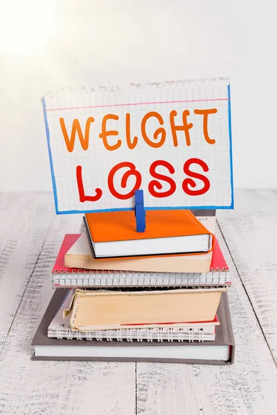 Text sign showing Weight Loss. Conceptual photo a reduction of the total body mass due to a mean loss of fluid pile stacked books notebook pin clothespin colored reminder white wooden.