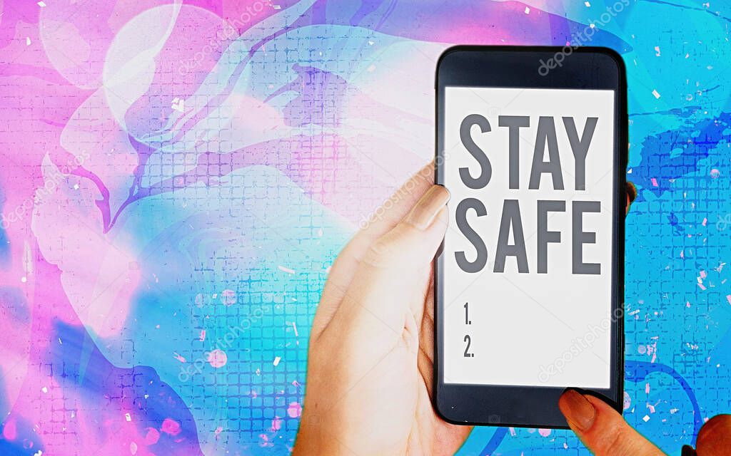 Word writing text Stay Safe. Business concept for secure from threat of danger, harm or place to keep articles Modern gadgets with white display screen under colorful bokeh background.