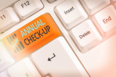 El yazısı metni, yıllık kontrol. Sağlık hizmeti sağlayıcısı ile yıllık üreme sağlığı ziyareti anlamına gelen kavram beyaz tuş alanının üzerinde boş not kağıdı bulunan beyaz pc klavyesi.