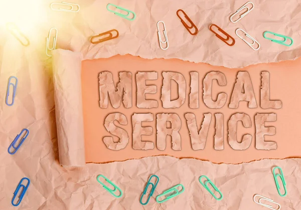 Conceptual hand writing showing Medical Service. Business photo text care and treatment provided by a licensed medical provider Rolled ripped torn cardboard above a wooden classic table.